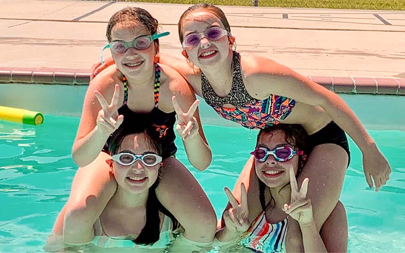 Four sisters swimming in heated pool at Cedar Rapids Lodge