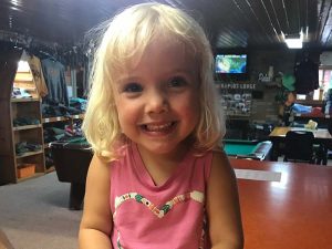Young girl smiling at Cedar Rapids Lodge with pool table in the background